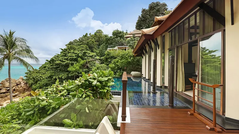 Deck overlooking ocean, bordered by lush greenery and pool at Banyan Tree Samui partial ocean-view pool villa.