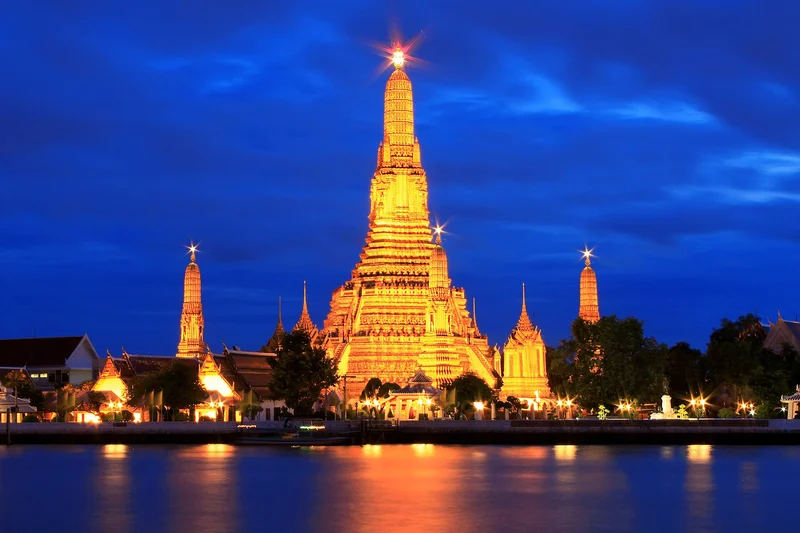 Wat Arun illuminated beside the Chao Phraya River at blue hour, Bangkok
